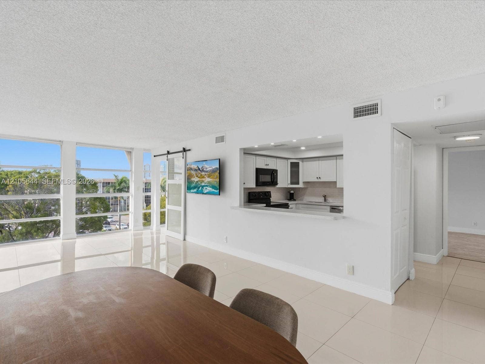 2101 Atlantic Shores Boulevard, #502, Hallandale Beach, Hallandale Beach, FL 33009 Large floor-to-ceiling windows, porcelain tile flooring, kitchen pass-through with breakfast bar, and sliding barn-style door