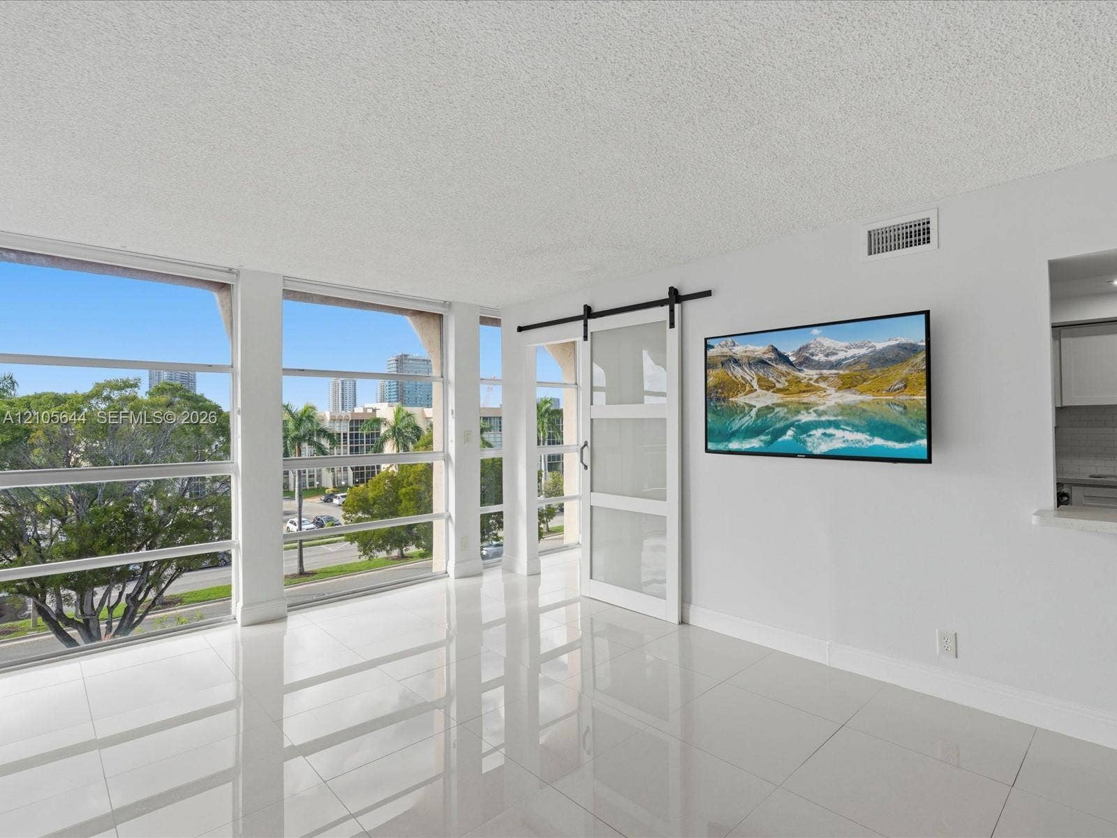 2101 Atlantic Shores Boulevard, #502, Hallandale Beach, Hallandale Beach, FL 33009 Floor-to-ceiling windows, white tile flooring, and a sliding glass barn door with a black metal track system