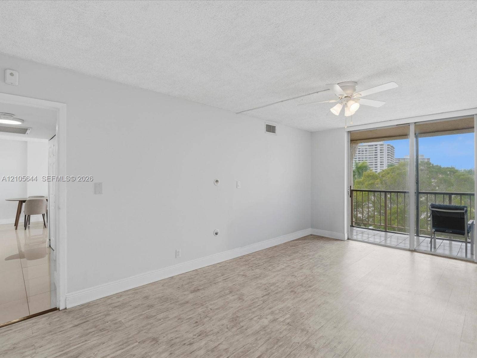 2101 Atlantic Shores Boulevard, #502, Hallandale Beach, Hallandale Beach, FL 33009 Living area featuring wood-finish flooring, a ceiling fan with integrated lighting, and sliding glass doors opening to a balcony with metal railings