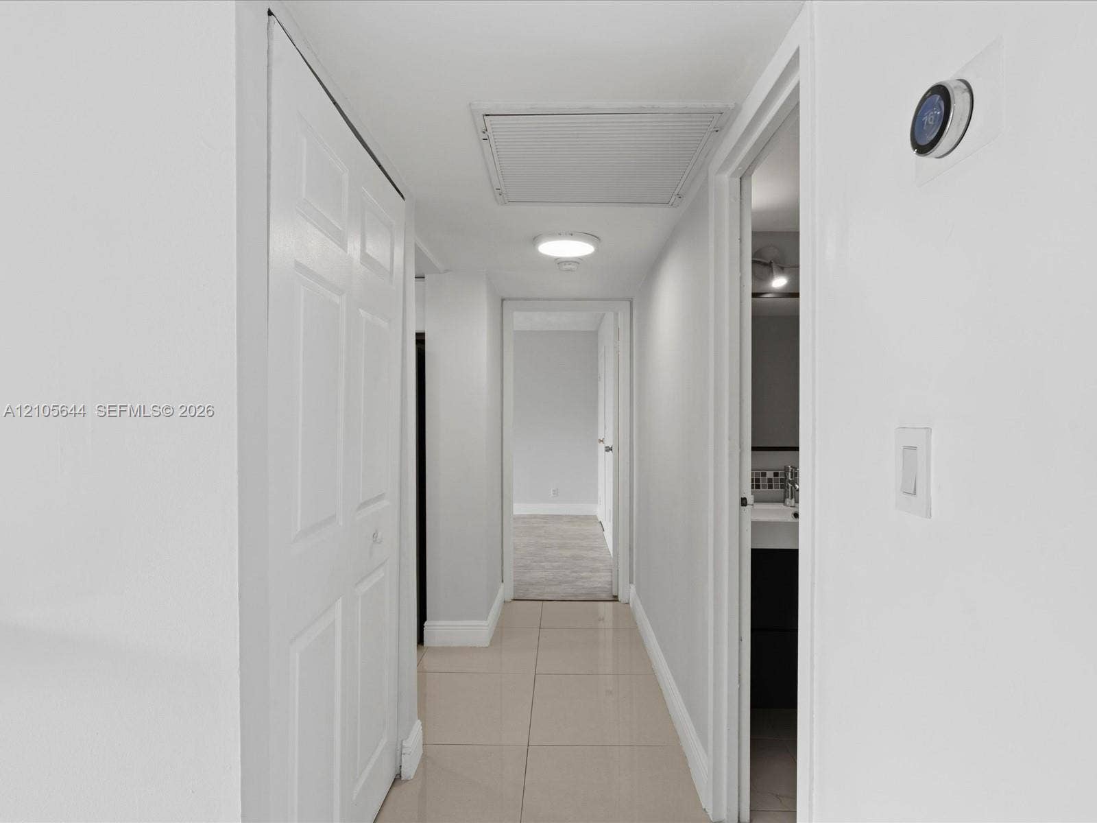 2101 Atlantic Shores Boulevard, #502, Hallandale Beach, Hallandale Beach, FL 33009 Hallway featuring large-format ceramic tile flooring, double-panel closet doors, ceiling-mounted light fixture, and smart thermostat