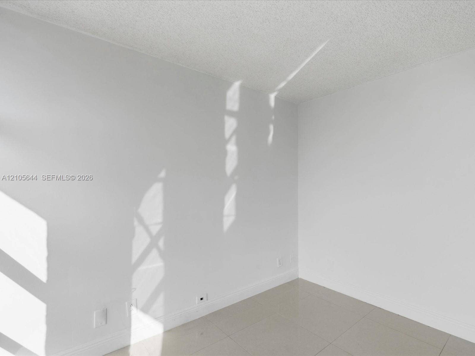 2101 Atlantic Shores Boulevard, #502, Hallandale Beach, Hallandale Beach, FL 33009 Neutral-toned interior space featuring light-colored tile flooring, smooth-finish walls, and a textured ceiling