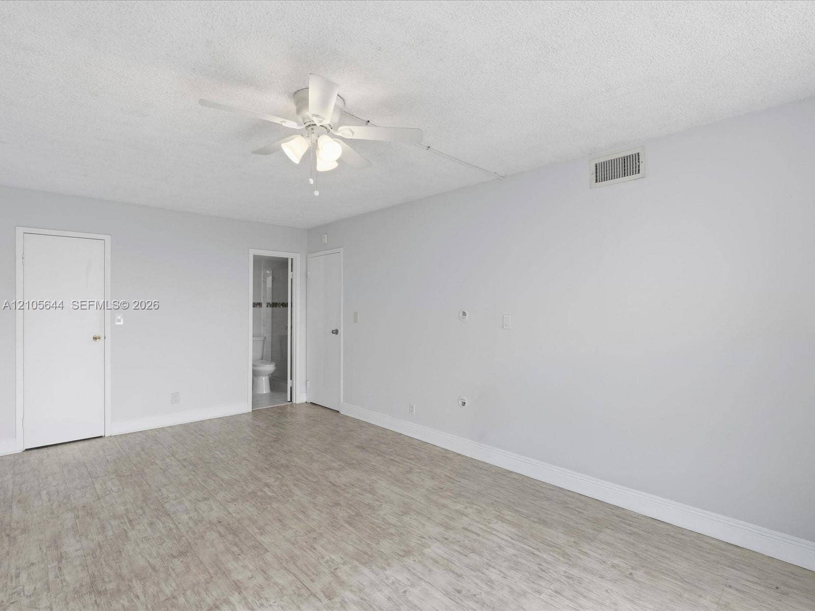 2101 Atlantic Shores Boulevard, #502, Hallandale Beach, Hallandale Beach, FL 33009 Neutral-toned room featuring wood-finish flooring, a central ceiling fan with integrated lighting, and multiple interior doors