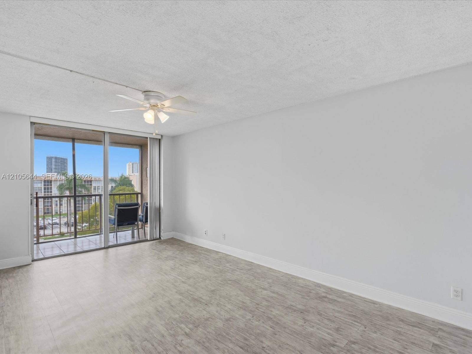 2101 Atlantic Shores Boulevard, #502, Hallandale Beach, Hallandale Beach, FL 33009 Neutral interior featuring wood-finish flooring, a ceiling-mounted light fixture with fan, and a floor-to-ceiling glass sliding door providing exterior access to a private balcony