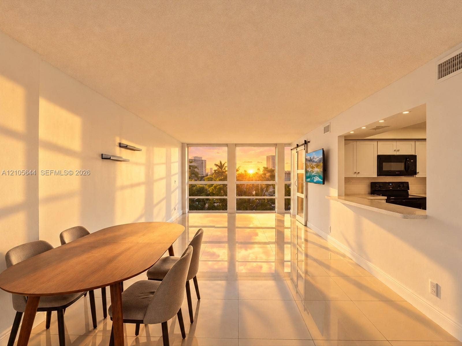 2101 Atlantic Shores Boulevard, #502, Hallandale Beach, Hallandale Beach, FL 33009 Open-concept interior featuring large-format tile flooring, expansive floor-to-ceiling windows, and a kitchen pass-through with a built-in breakfast bar