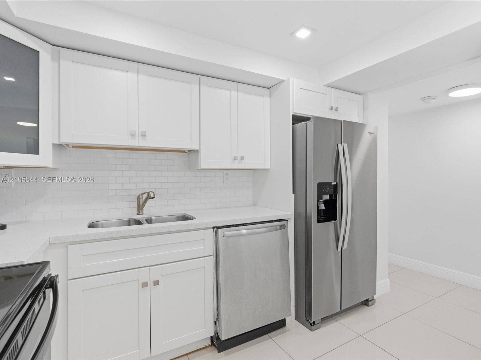 2101 Atlantic Shores Boulevard, #502, Hallandale Beach, Hallandale Beach, FL 33009 Kitchen featuring white shaker-style cabinetry, a white subway tile backsplash, stainless steel appliances, a double-basin sink, and tile flooring