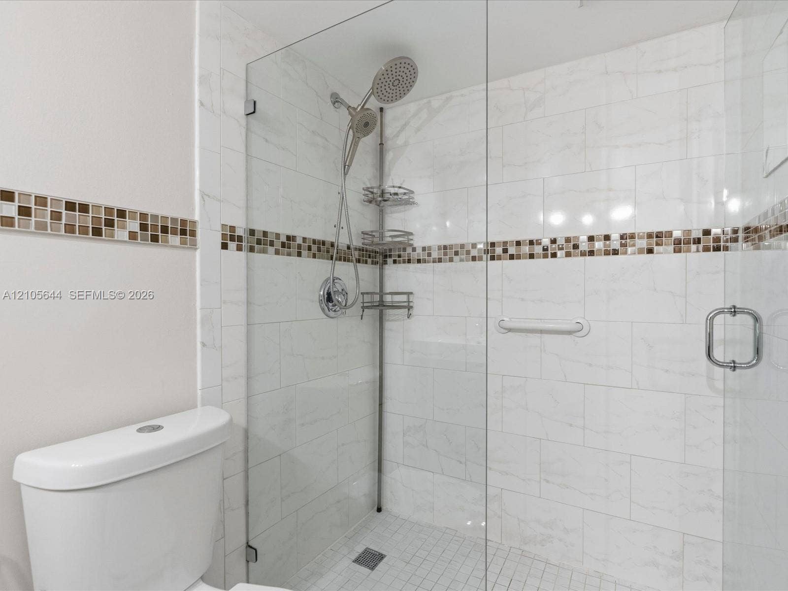 2101 Atlantic Shores Boulevard, #502, Hallandale Beach, Hallandale Beach, FL 33009 Walk-in shower featuring large-format white tile, glass enclosure, mosaic tile border, handheld shower fixture, and integrated grab bar