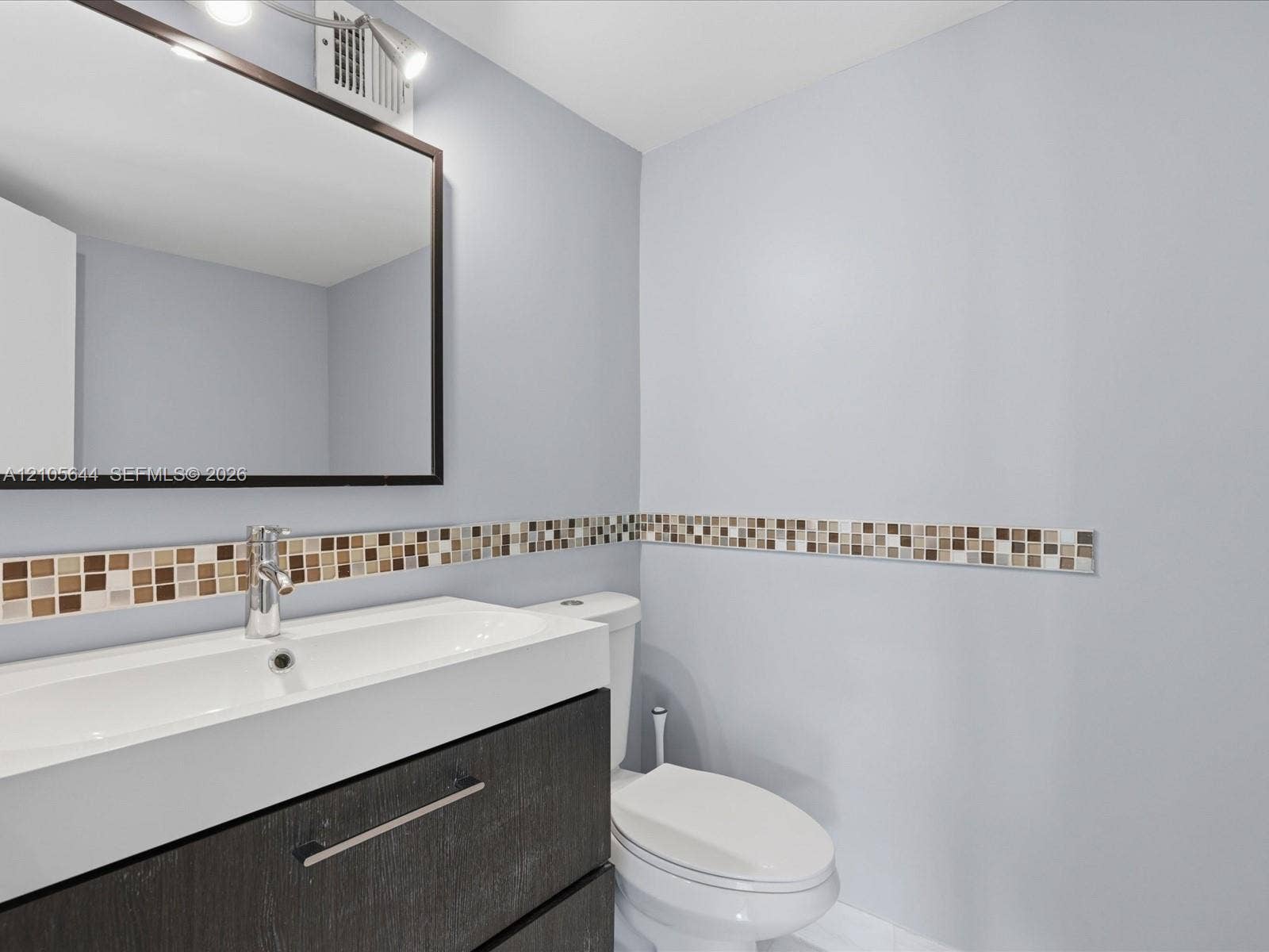 2101 Atlantic Shores Boulevard, #502, Hallandale Beach, Hallandale Beach, FL 33009 Floating vanity with integrated sink, rectangular framed mirror, chrome fixtures, and mosaic tile wall accent
