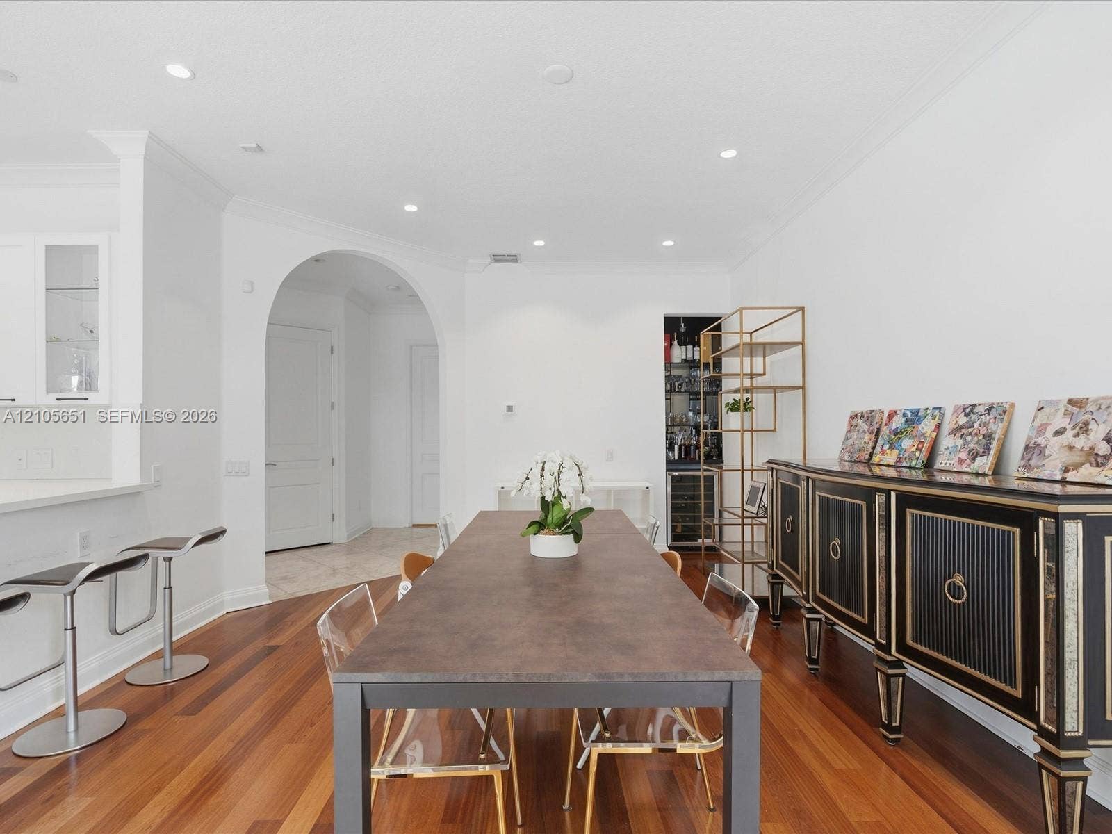 Dining area featuring wood-finish flooring, recessed lighting, a large architectural archway, and a built-in refrigerated wine storage niche