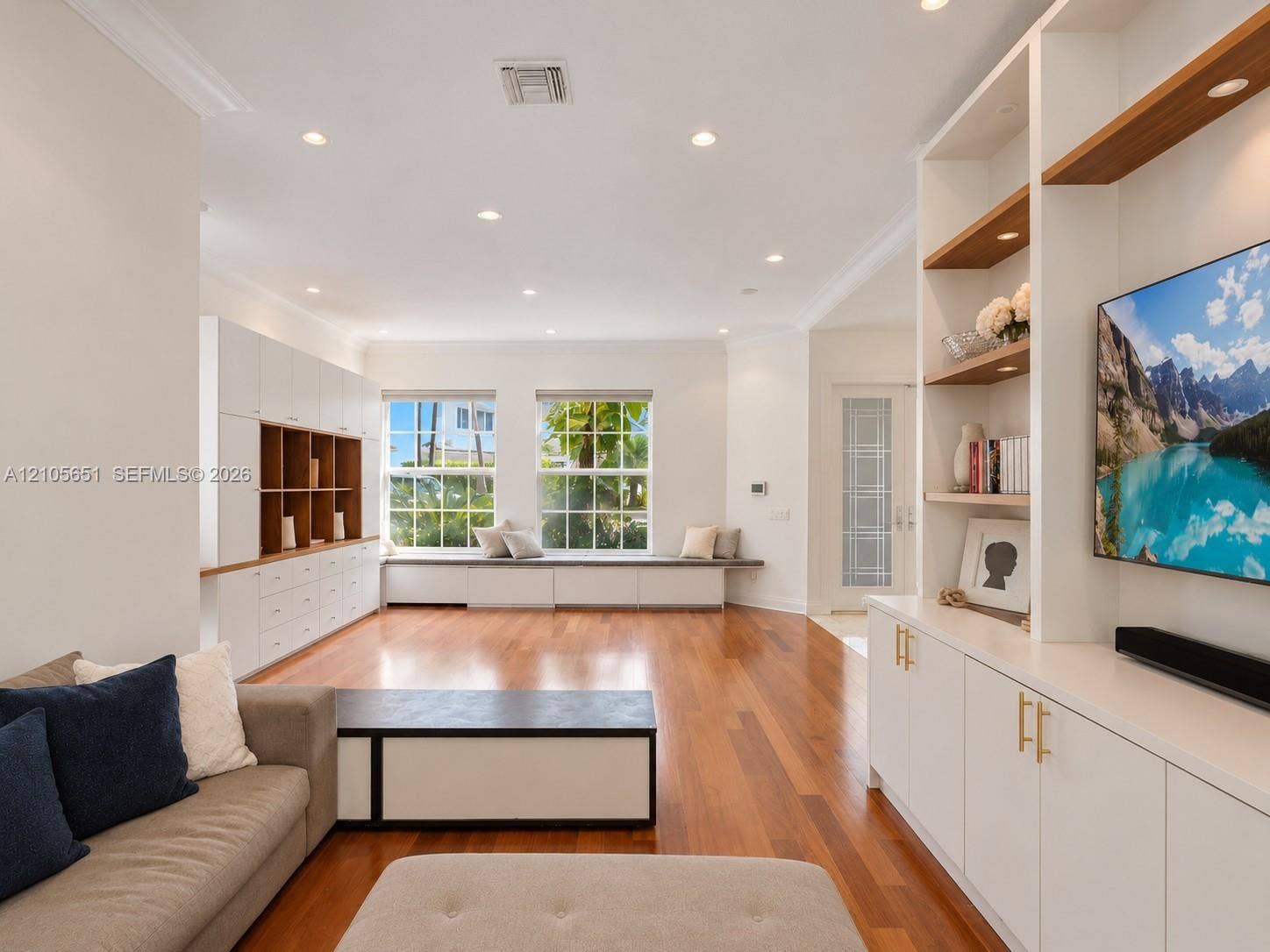 Living space featuring wood-finish flooring, recessed lighting, expansive built-in cabinetry, custom shelving, and a window seat