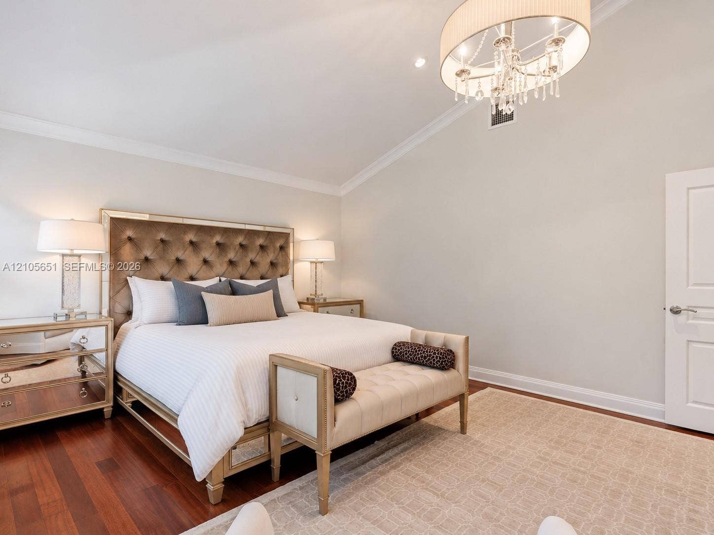 Vaulted ceiling featuring a crystal drum chandelier, wood-finish flooring, and a multi-panel interior door