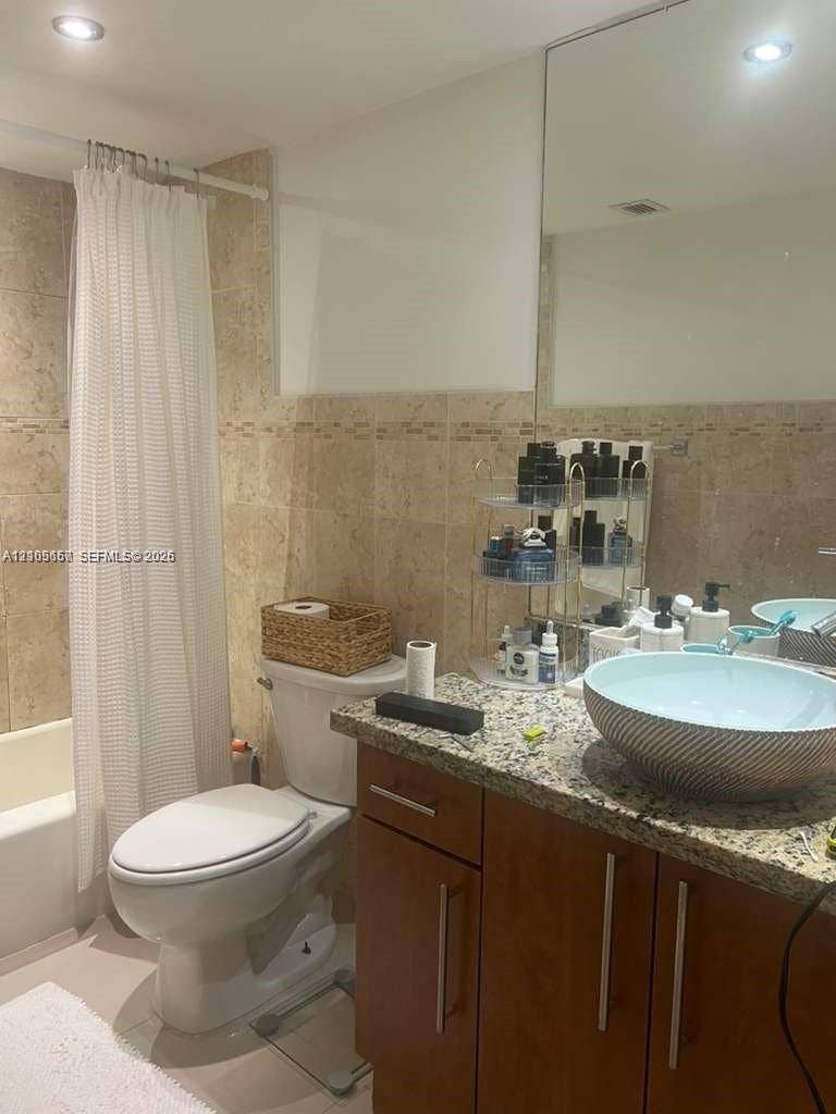 19380 Collins Avenue, #808, Sunny Isles Beach, FL 33160 Bathroom featuring natural stone wall tile, vessel sink, stone-surface countertop, wood-finish cabinetry, and recessed lighting