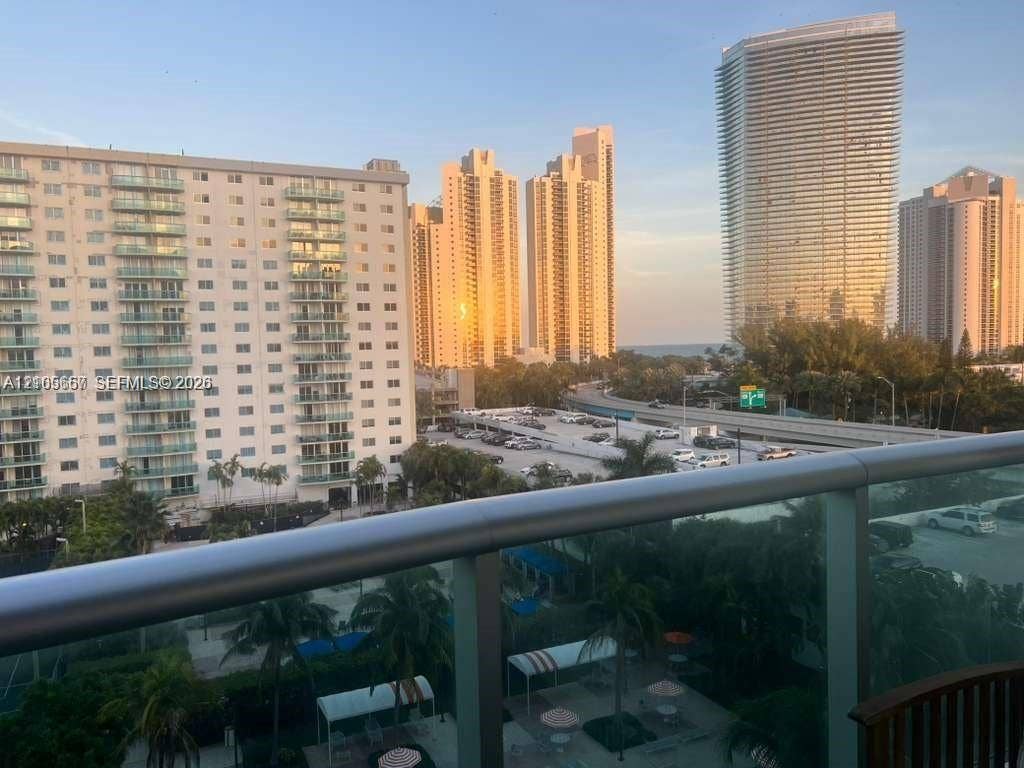 19380 Collins Avenue, #808, Sunny Isles Beach, FL 33160 Elevated balcony featuring a glass panel railing and a panoramic perspective of the cityscape and coastal horizon