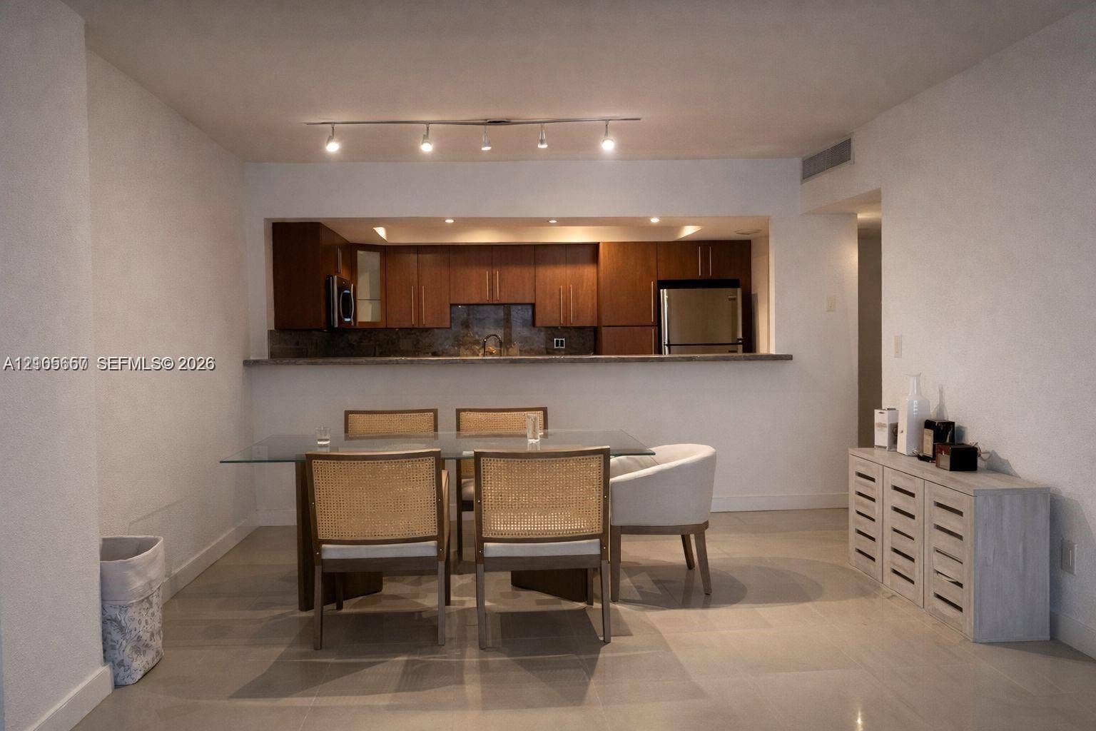 19380 Collins Avenue, #808, Sunny Isles Beach, FL 33160 Kitchen featuring dark wood-finish cabinetry, stainless steel appliances, and a breakfast bar counter, illuminated by track lighting