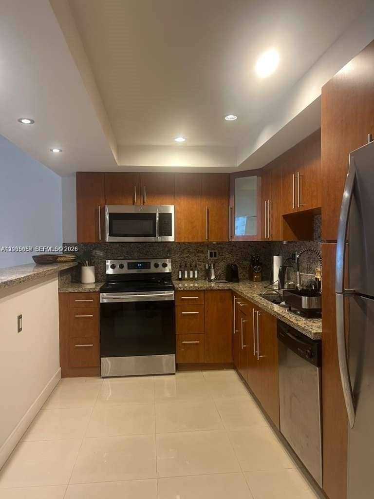 19380 Collins Avenue, #808, Sunny Isles Beach, FL 33160 Kitchen featuring wood cabinetry, stone-surface countertops, stainless steel appliances, recessed ceiling lighting, and tile flooring