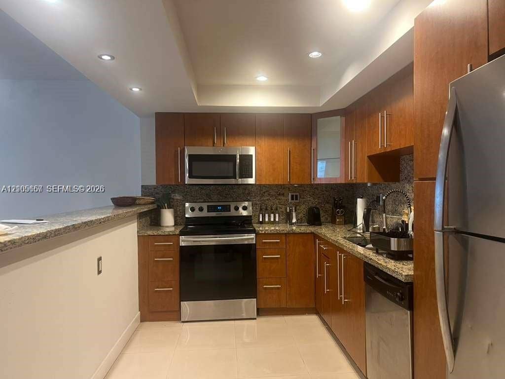 19380 Collins Avenue, #808, Sunny Isles Beach, FL 33160 Kitchen featuring wood cabinetry, stone countertops, stainless steel appliances, recessed ceiling lighting, and a breakfast bar
