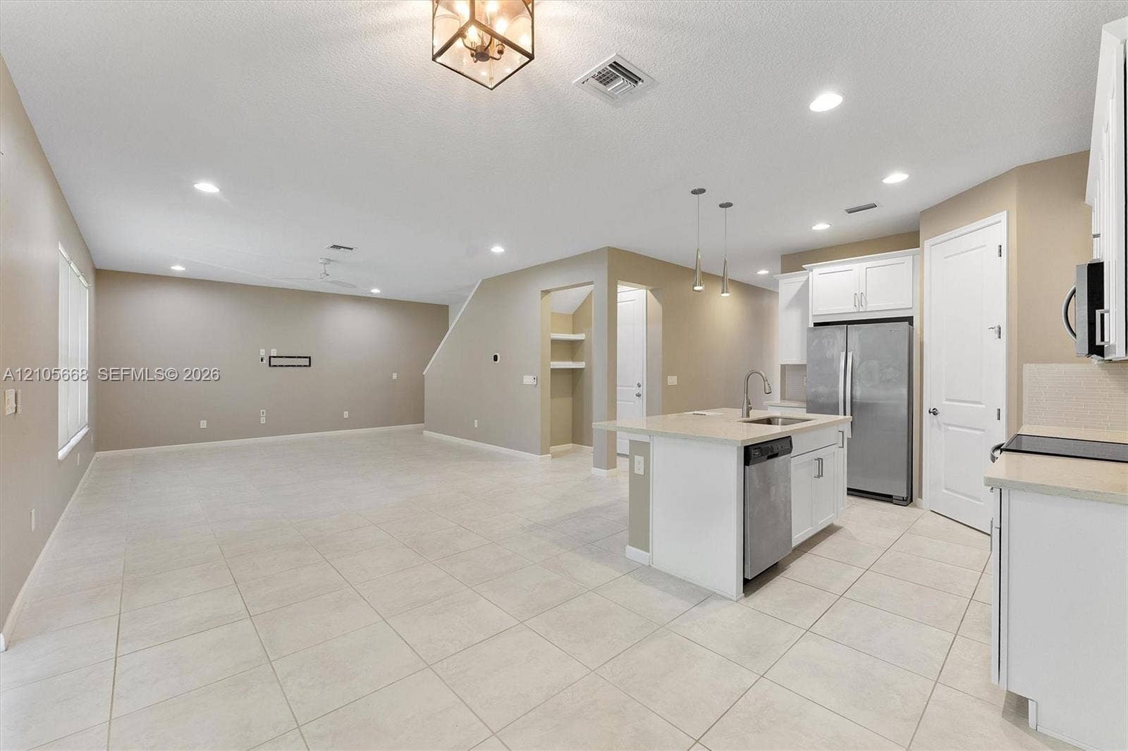 6307 Trails Of Foxford Court, West Palm Beach, FL 33415 Open-concept space featuring ceramic tile flooring, recessed lighting, kitchen island with integrated stainless steel sink, white shaker-style cabinetry, and stainless steel appliances