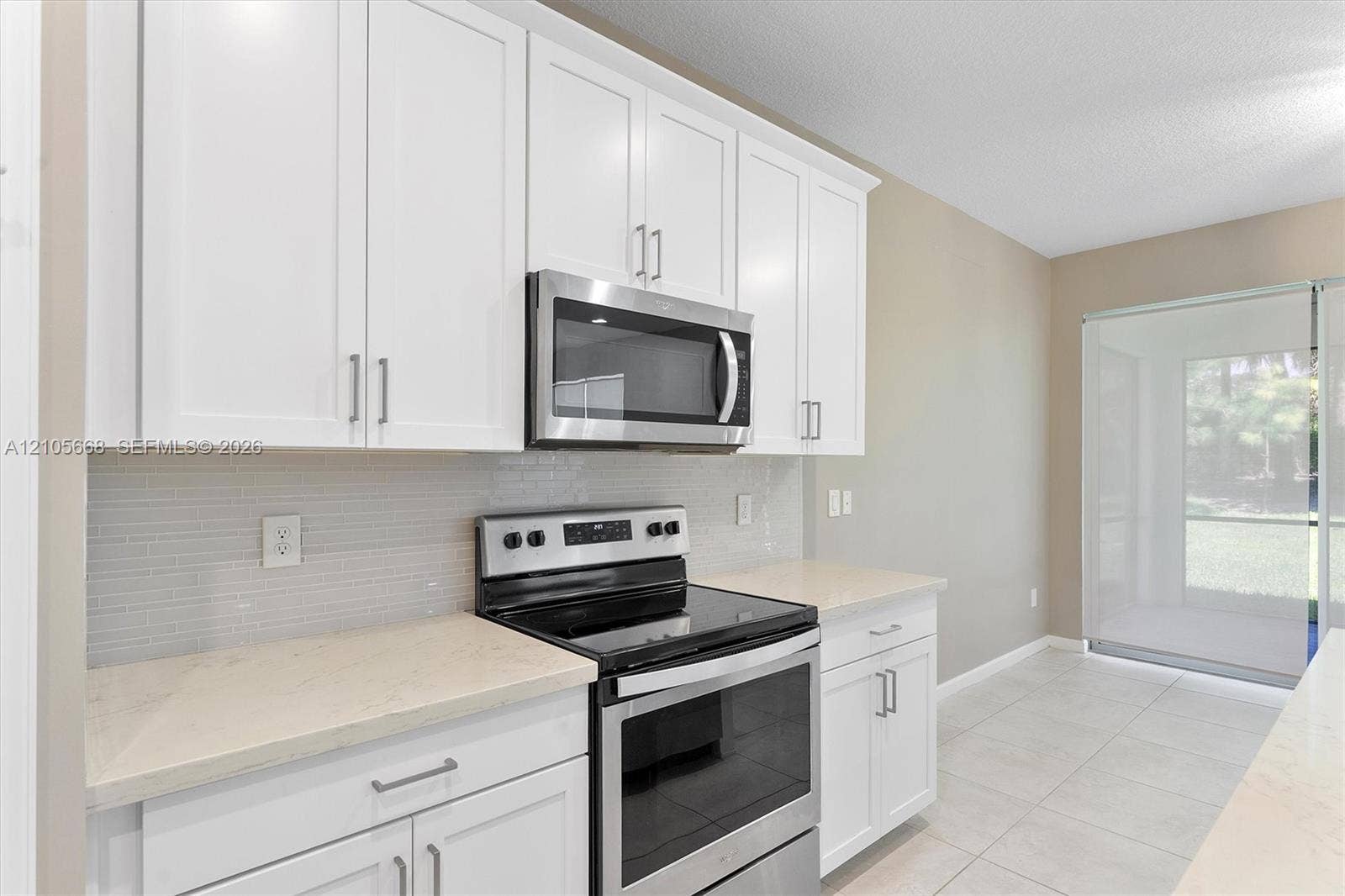 6307 Trails Of Foxford Court, West Palm Beach, FL 33415 Kitchen featuring white cabinetry, stainless steel appliances, neutral countertops, linear tile backsplash, and ceramic tile flooring