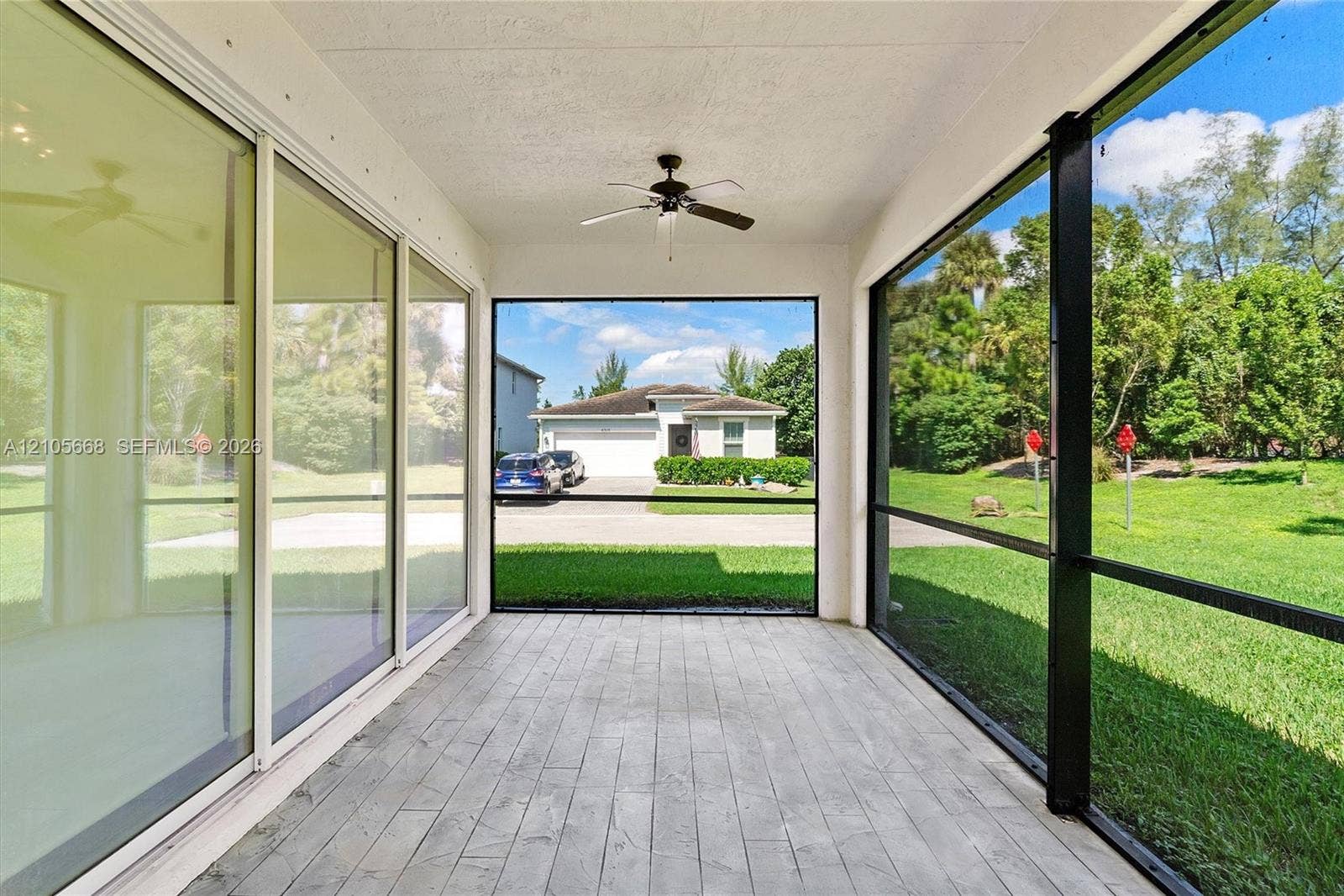 6307 Trails Of Foxford Court, West Palm Beach, FL 33415 Screened-in lanai featuring wood-look tile flooring, ceiling fan, and sliding glass door entry