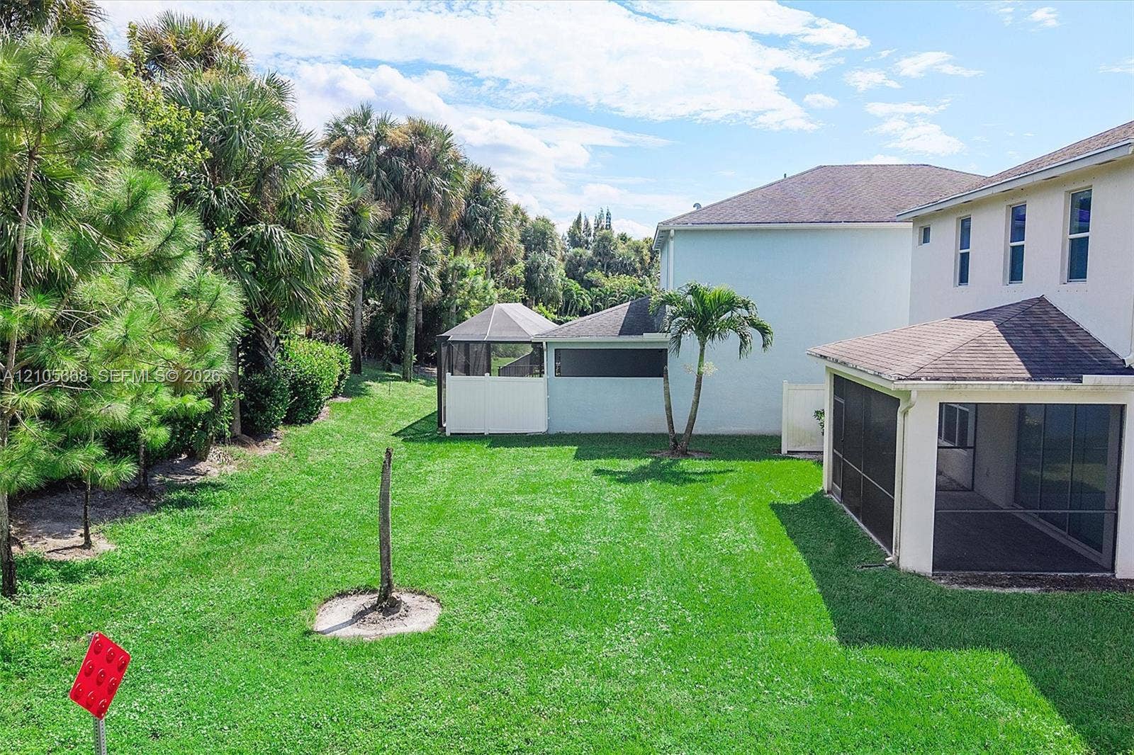 6307 Trails Of Foxford Court, West Palm Beach, FL 33415 Backyard featuring a screened-in lanai, manicured lawn, established palm trees, and perimeter landscaping