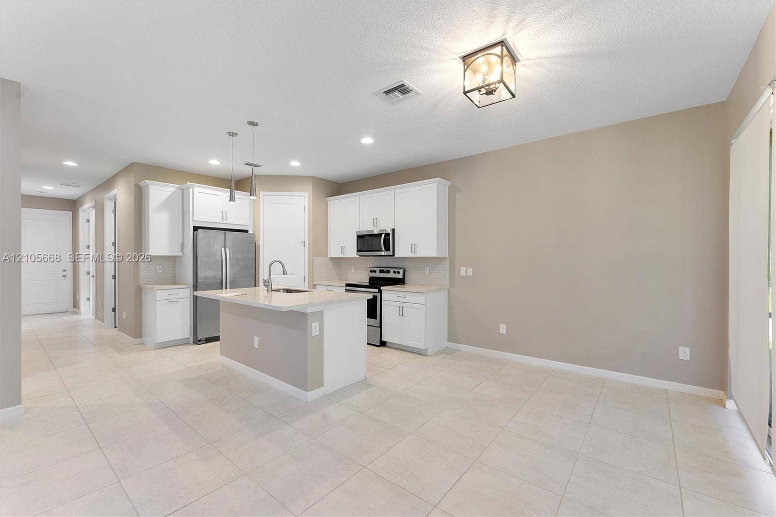 6307 Trails Of Foxford Court, West Palm Beach, FL 33415 Kitchen featuring white cabinetry, center island with stone-finish countertop, stainless steel appliances, neutral tile flooring, and metallic pendant lighting