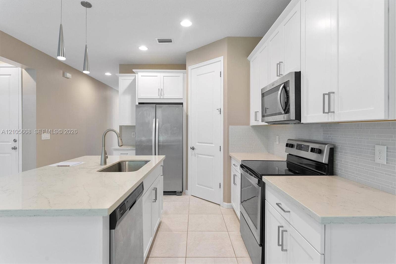 6307 Trails Of Foxford Court, West Palm Beach, FL 33415 Modern kitchen featuring white cabinetry with stainless steel hardware, quartz countertops, and a large waterfall-edge island with undermount sink