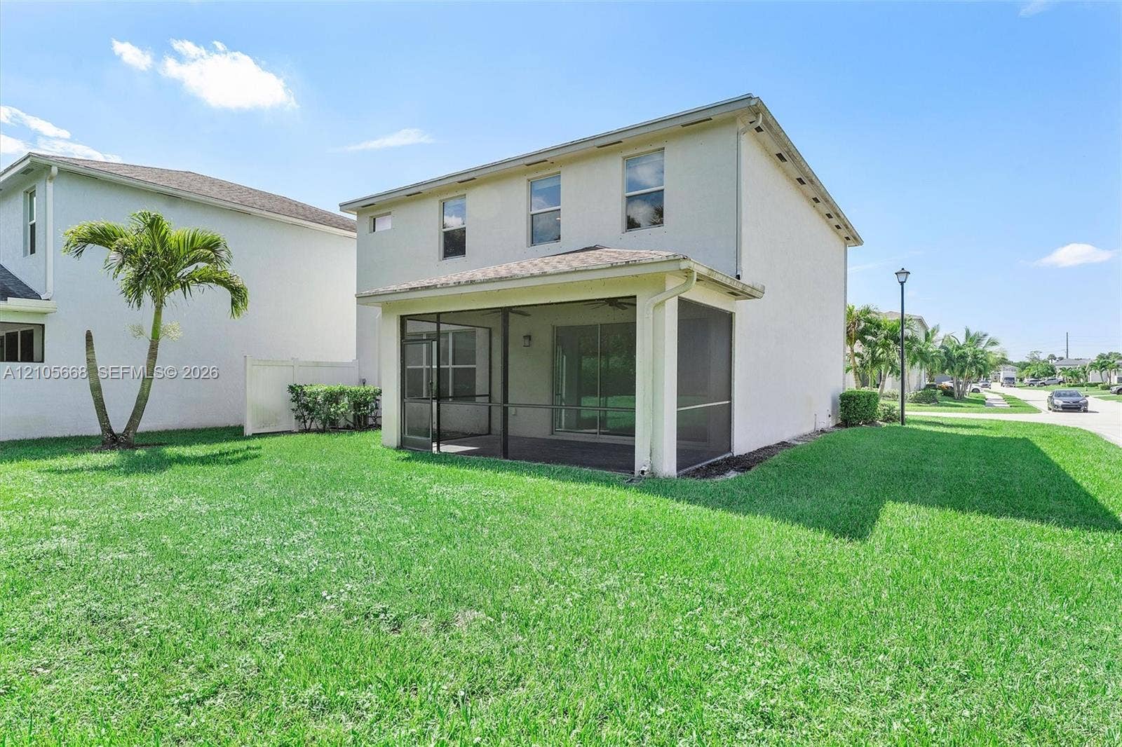 6307 Trails Of Foxford Court, West Palm Beach, FL 33415 Two-story exterior featuring a stucco facade, screened-in rear lanai, and expansive lawn