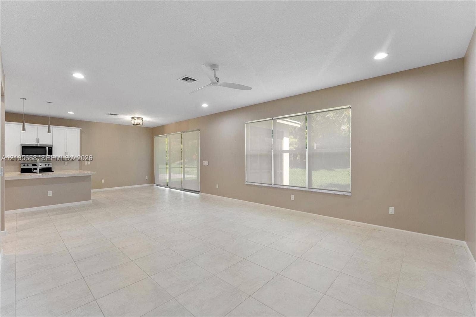 6307 Trails Of Foxford Court, West Palm Beach, FL 33415 Open-concept interior featuring neutral wall tones, large-format tile flooring, recessed lighting, white cabinetry with built-in microwave, and oversized windows