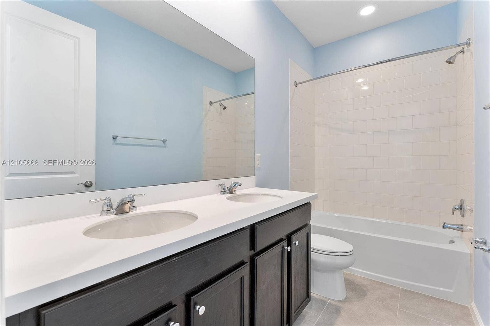 6307 Trails Of Foxford Court, West Palm Beach, FL 33415 Bathroom featuring a double-sink vanity with a solid-surface countertop, full-width vanity mirror, tile flooring, and a bathtub-shower combination with tile surround