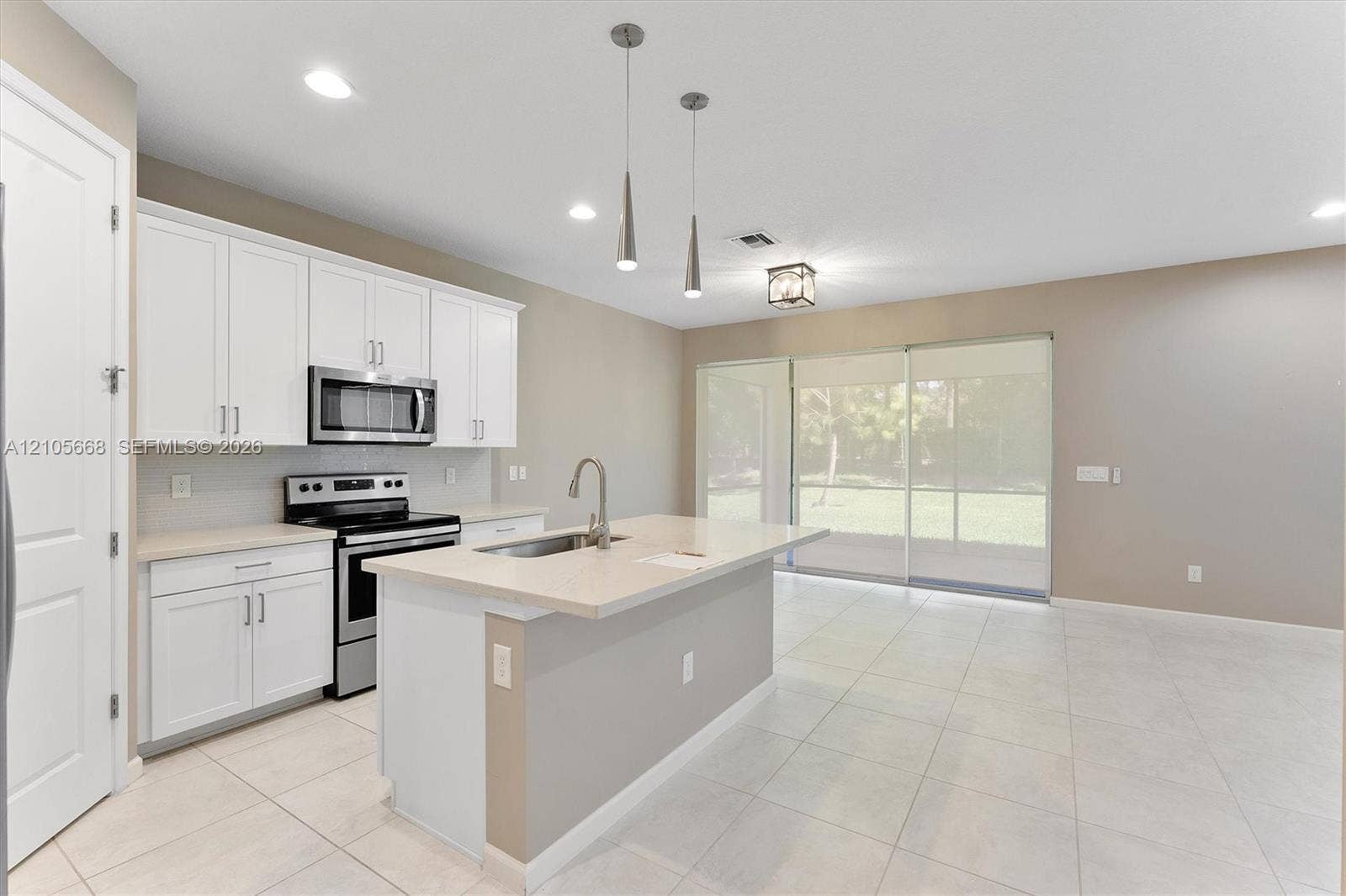 6307 Trails Of Foxford Court, West Palm Beach, FL 33415 Kitchen featuring white shaker-style cabinetry, a central island with a solid-surface countertop, stainless steel appliances, dual pendant lighting, and neutral tile flooring