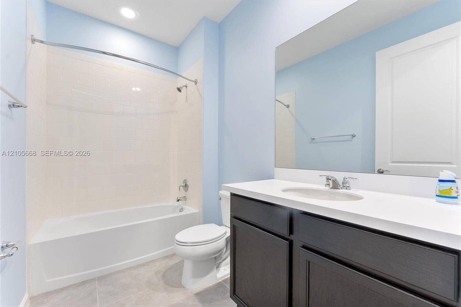 6307 Trails Of Foxford Court, West Palm Beach, FL 33415 Bathroom featuring a vanity with a white countertop and rectangular sink, dark cabinetry, a full-width vanity mirror, a bathtub-shower combination with tiled surround, and tile flooring