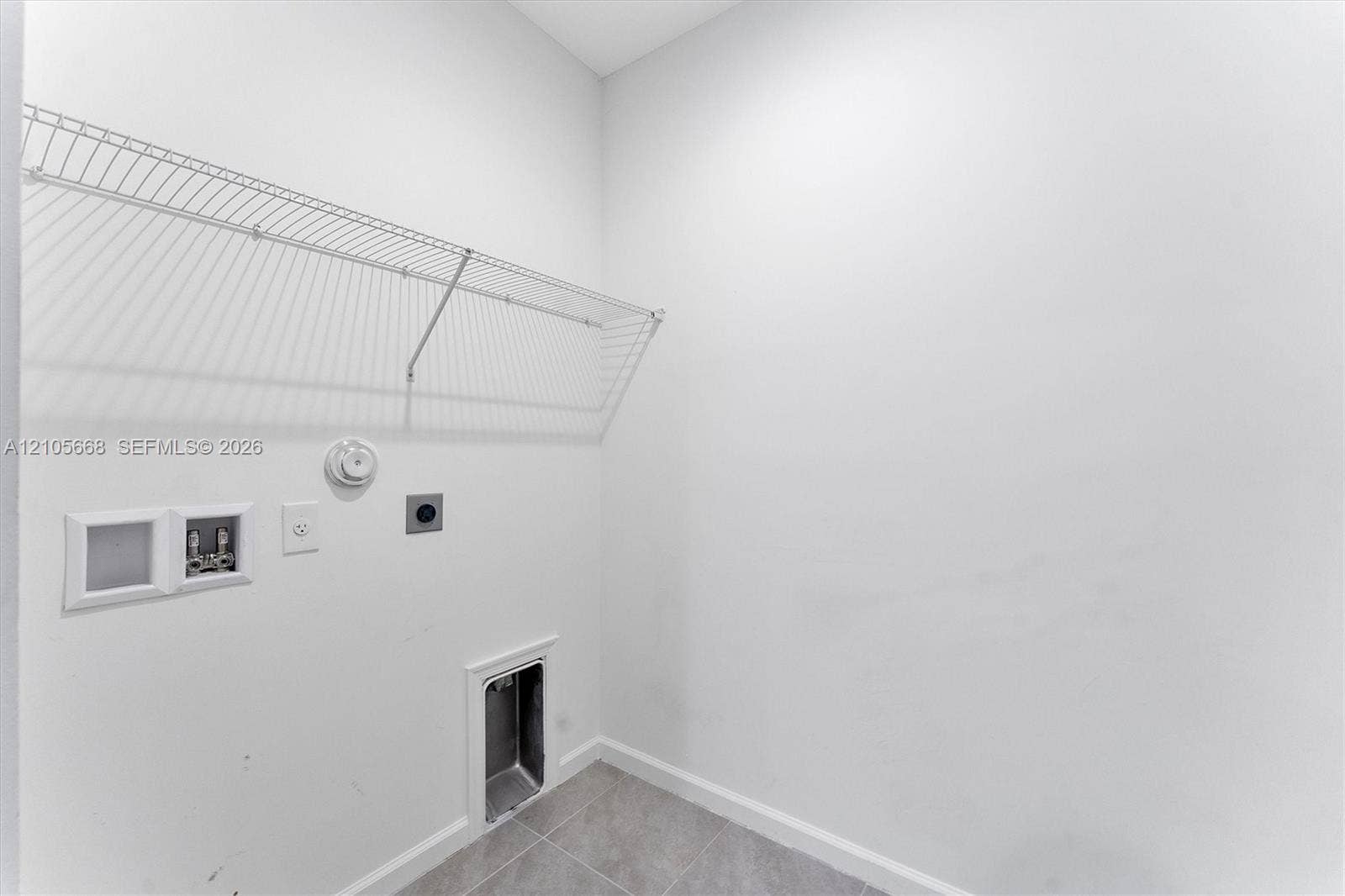 6307 Trails Of Foxford Court, West Palm Beach, FL 33415 Utility area featuring white walls, gray tile flooring, installed wire shelving, and recessed plumbing connections