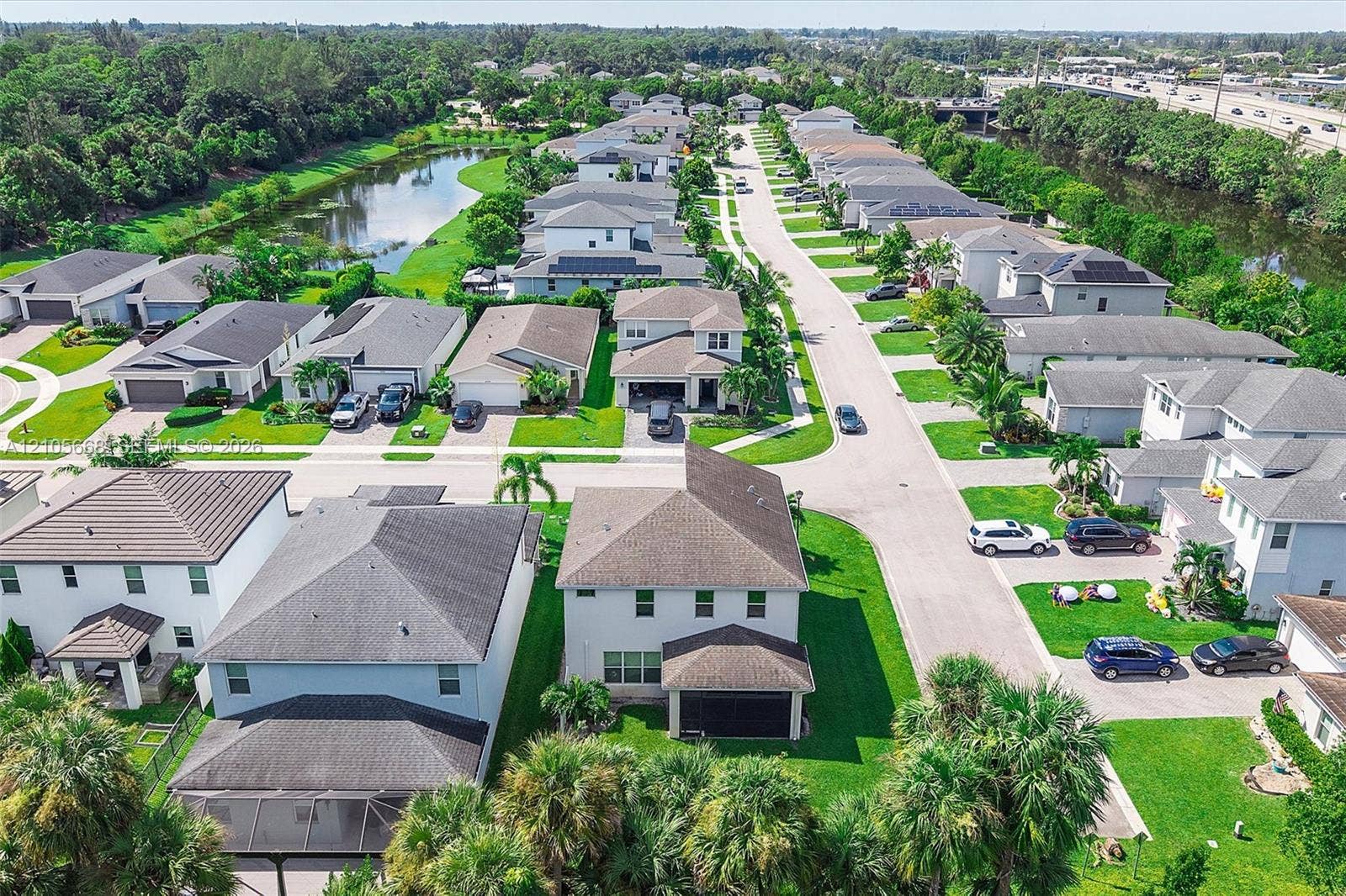 6307 Trails Of Foxford Court, West Palm Beach, FL 33415 Aerial perspective of a suburban neighborhood featuring paved streets, multi-story single-family residences, manicured lawns, mature palm landscaping, and a central water feature