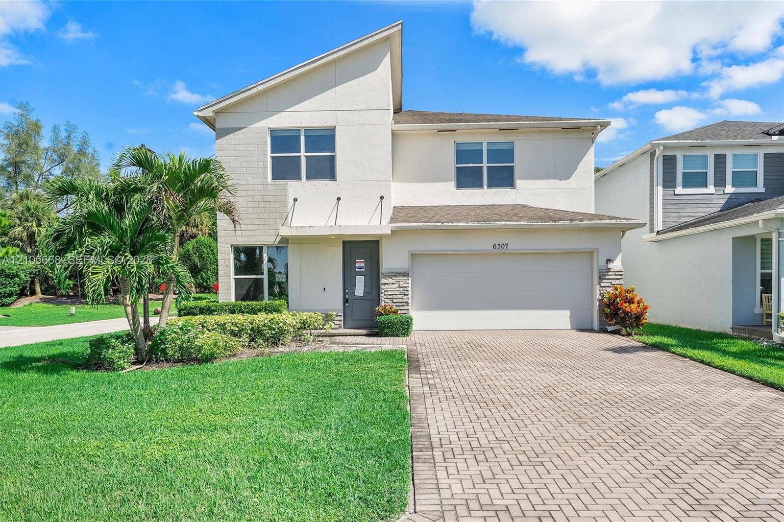 6307 Trails Of Foxford Court, West Palm Beach, FL 33415 Contemporary two-story exterior featuring a mix of stucco and stone veneer siding, an angular roofline, and a paved driveway