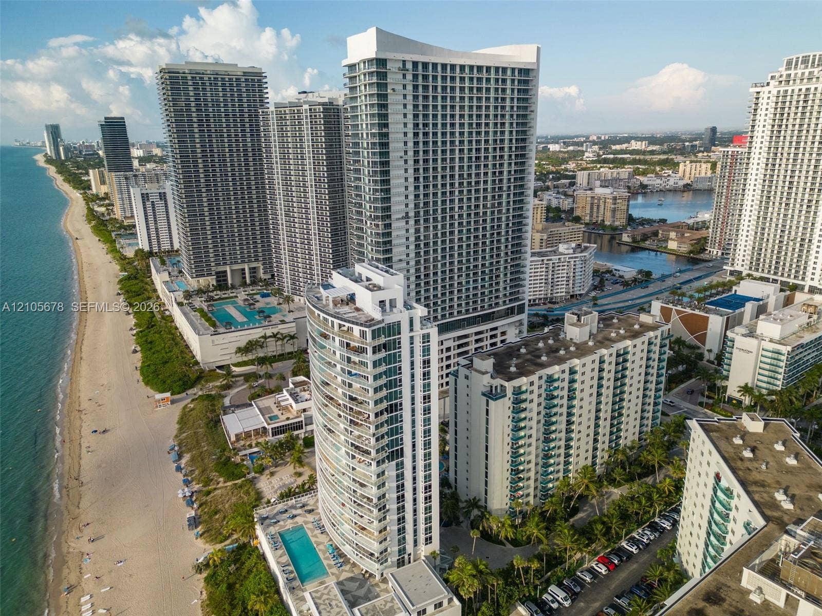 4001 S Ocean Drive, #14F, Hollywood, FL 33019 High-rise residential tower featuring floor-to-ceiling windows and private balconies, situated on a coastal shoreline with direct beach access and a ground-level swimming pool