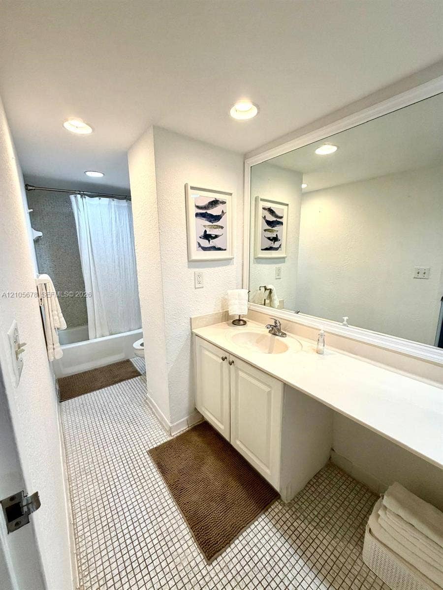 4001 S Ocean Drive, #14F, Hollywood, FL 33019 Bathroom featuring a large vanity with integrated countertop and sink, expansive wall-mounted mirror, recessed lighting, and a combination tub and shower enclosure with a tiled surround
