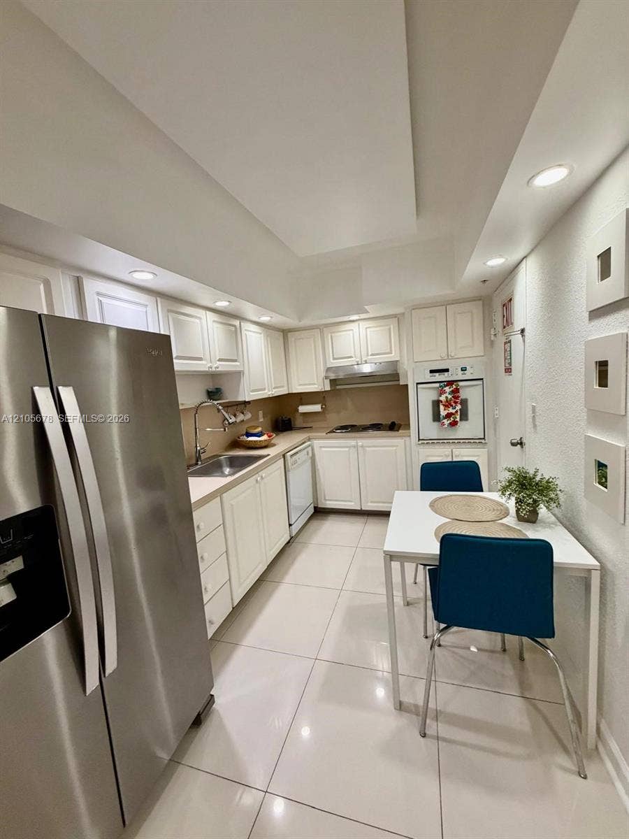 4001 S Ocean Drive, #14F, Hollywood, FL 33019 Kitchen featuring white cabinetry, stainless steel appliances, recessed ceiling lighting, and large-format tile flooring