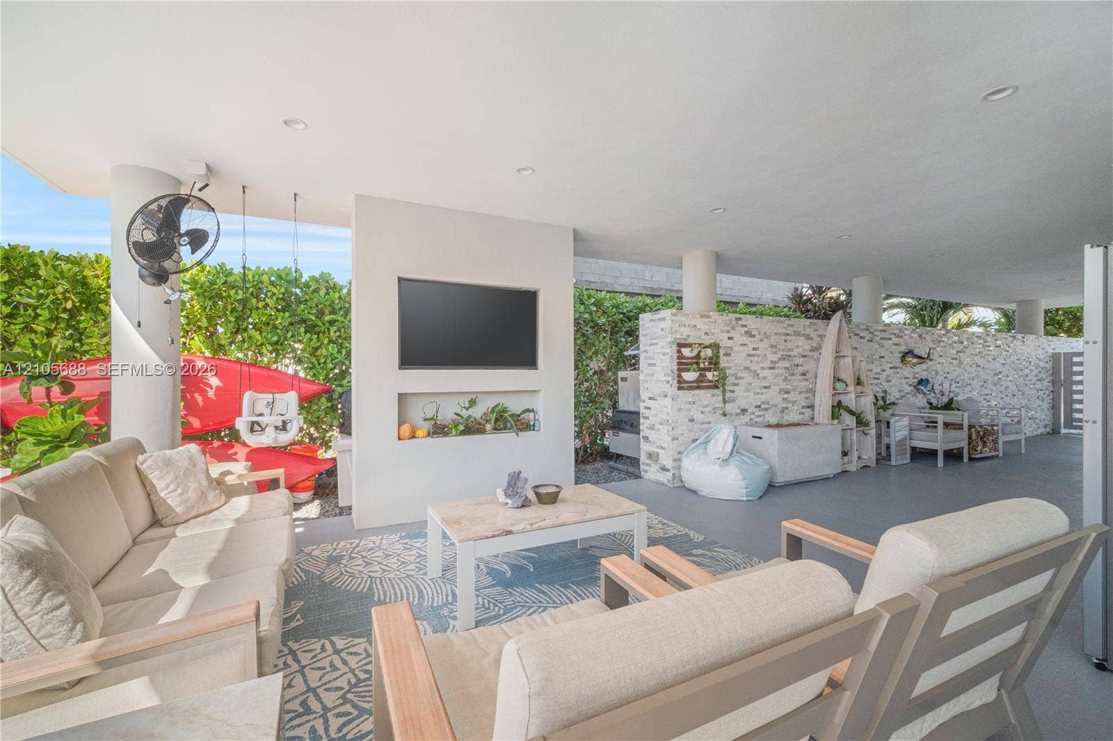 164 W Avenue C, Key Largo, FL 33037 Covered outdoor patio featuring recessed ceiling lighting, a textured stone accent wall, a built-in wall-mounted television, and a recessed display niche