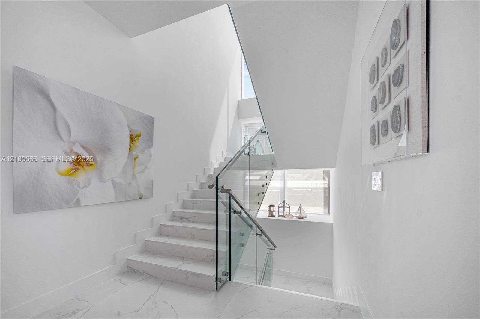 164 W Avenue C, Key Largo, FL 33037 Staircase featuring white stone-finish steps, glass balustrade, metal handrails, and a multi-level window design