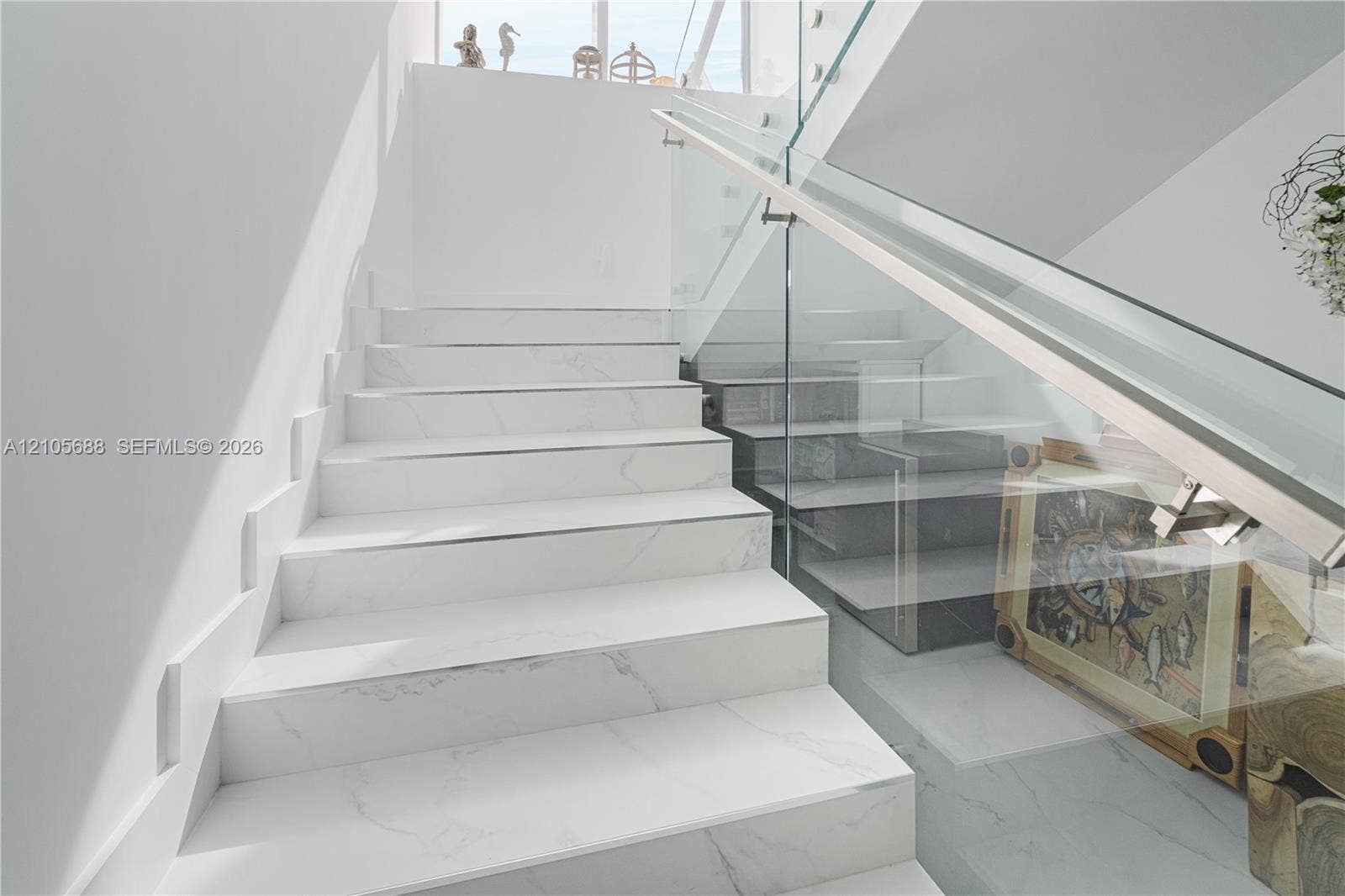 164 W Avenue C, Key Largo, FL 33037 Staircase featuring white stone-finish treads, glass railing panels, and a polished metal handrail