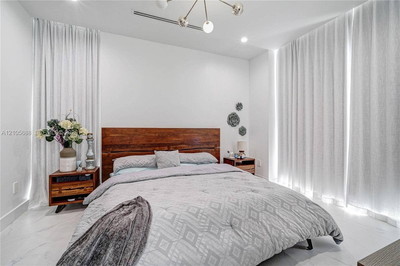 164 W Avenue C, Key Largo, FL 33037 Room featuring large-format light-toned tile flooring, floor-to-ceiling drapery, and a modern multi-bulb chandelier