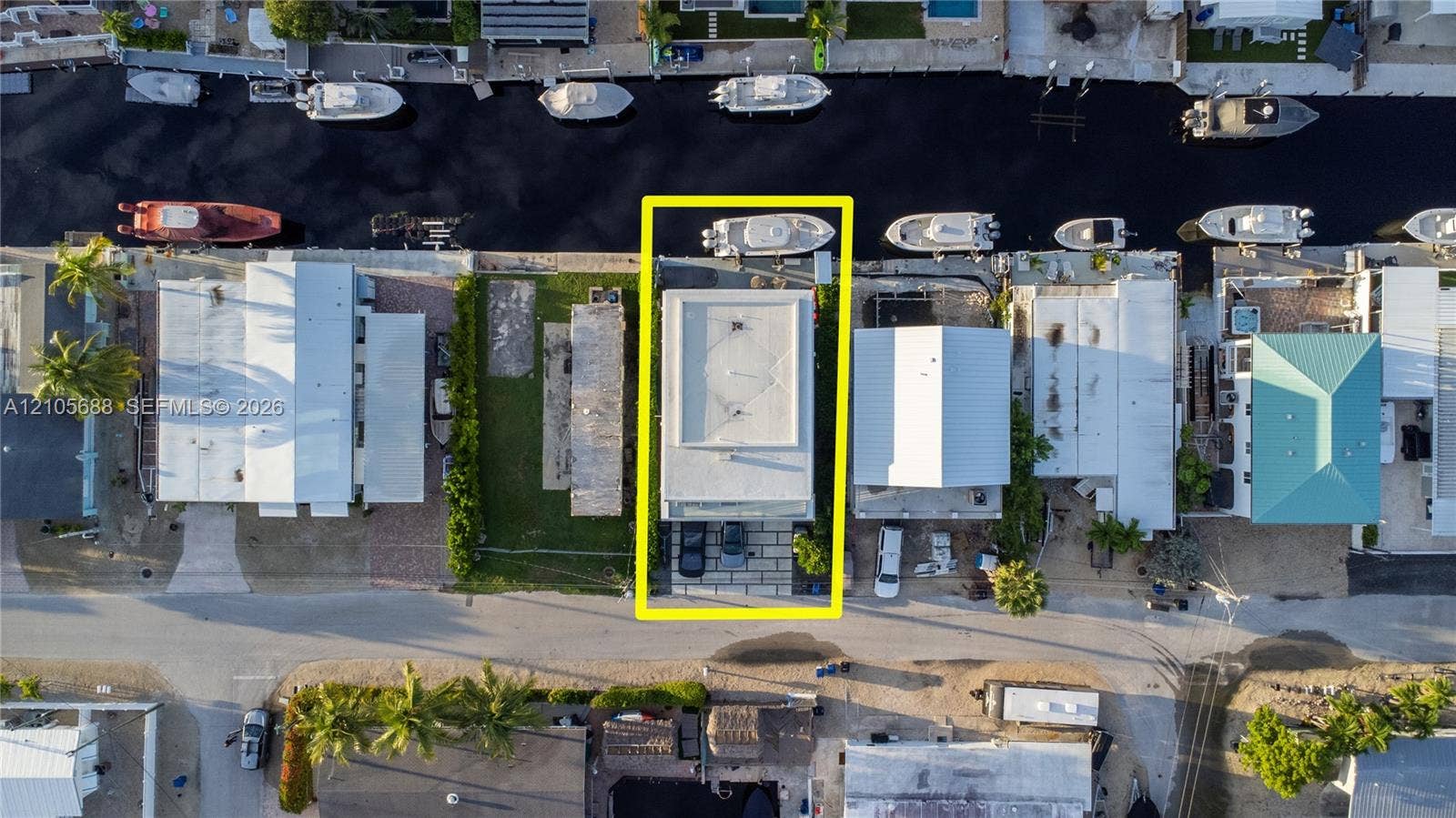 164 W Avenue C, Key Largo, FL 33037 Aerial perspective of a waterfront property featuring a paved driveway, private boat dock, and direct canal access