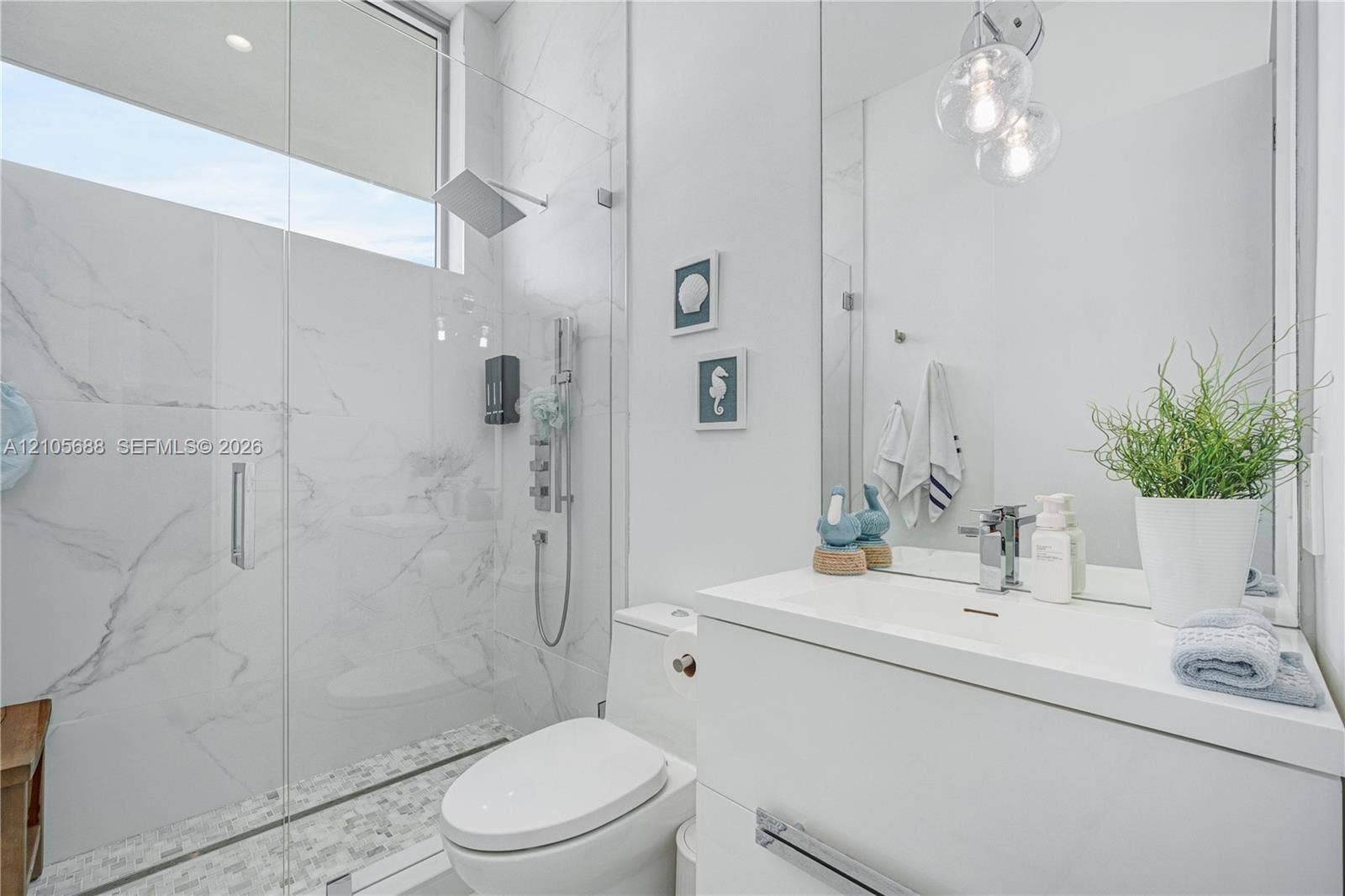 164 W Avenue C, Key Largo, FL 33037 Bathroom featuring a glass-enclosed walk-in shower with stone-patterned tile, a wall-mounted rainfall showerhead, a modern white vanity, and a transom window