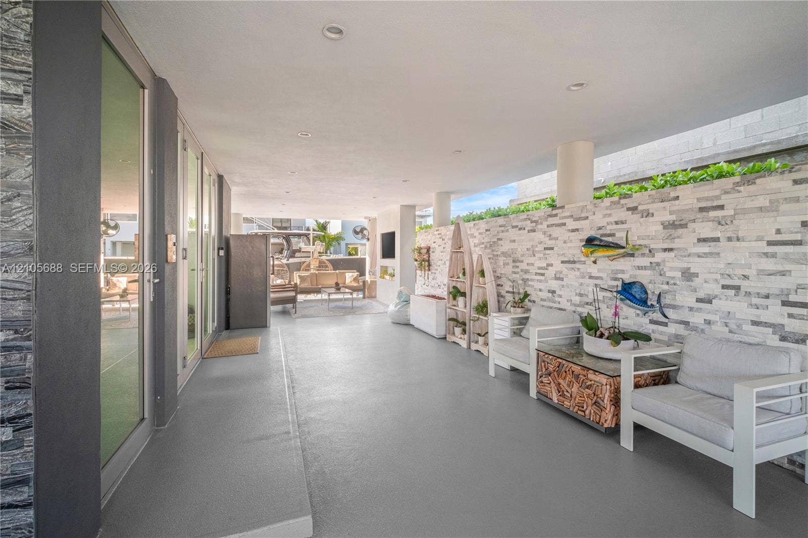 164 W Avenue C, Key Largo, FL 33037 Covered patio featuring a stacked stone accent wall, recessed lighting, concrete flooring, and full-height glass door panels