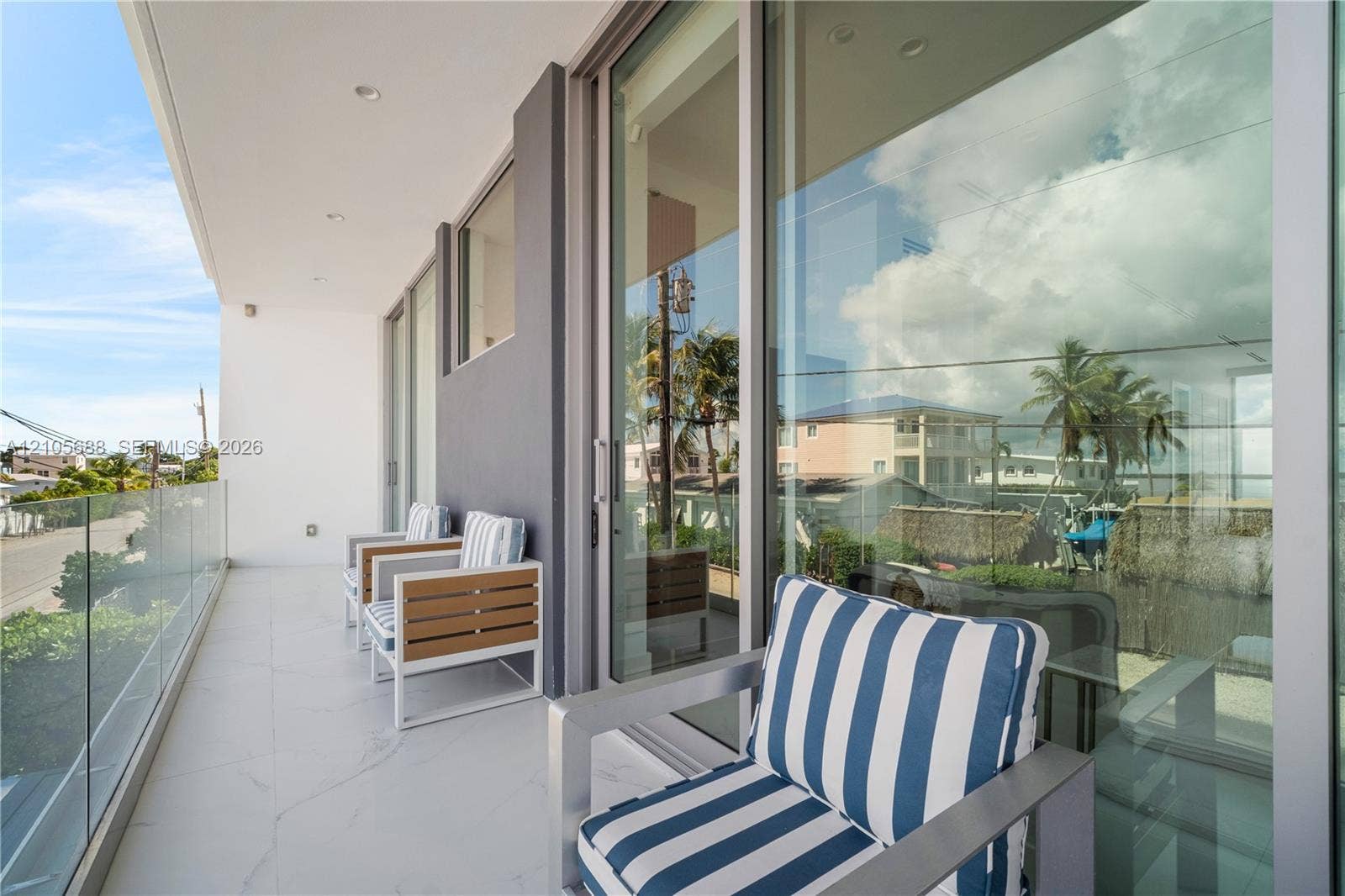164 W Avenue C, Key Largo, FL 33037 Expansive covered balcony with frameless glass railing, modern sliding glass doors, and polished concrete flooring
