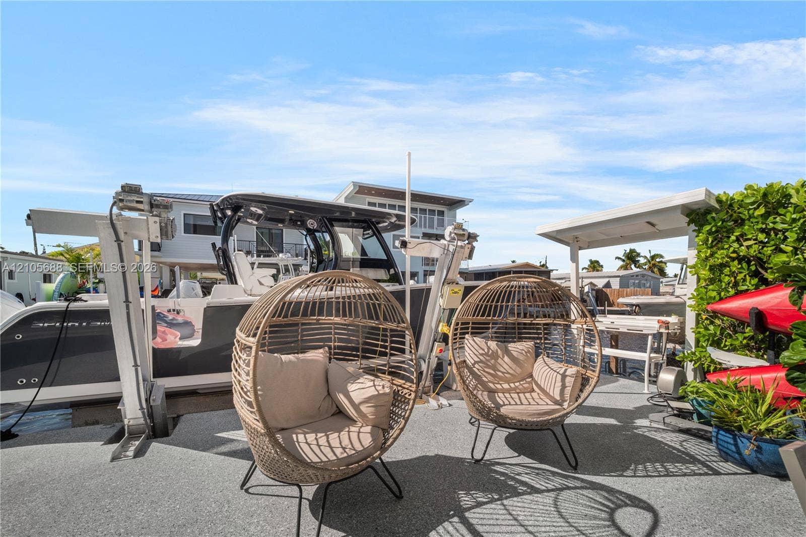 164 W Avenue C, Key Largo, FL 33037 Waterfront deck featuring a textured aggregate surface, boat lift system, and covered exterior workspace