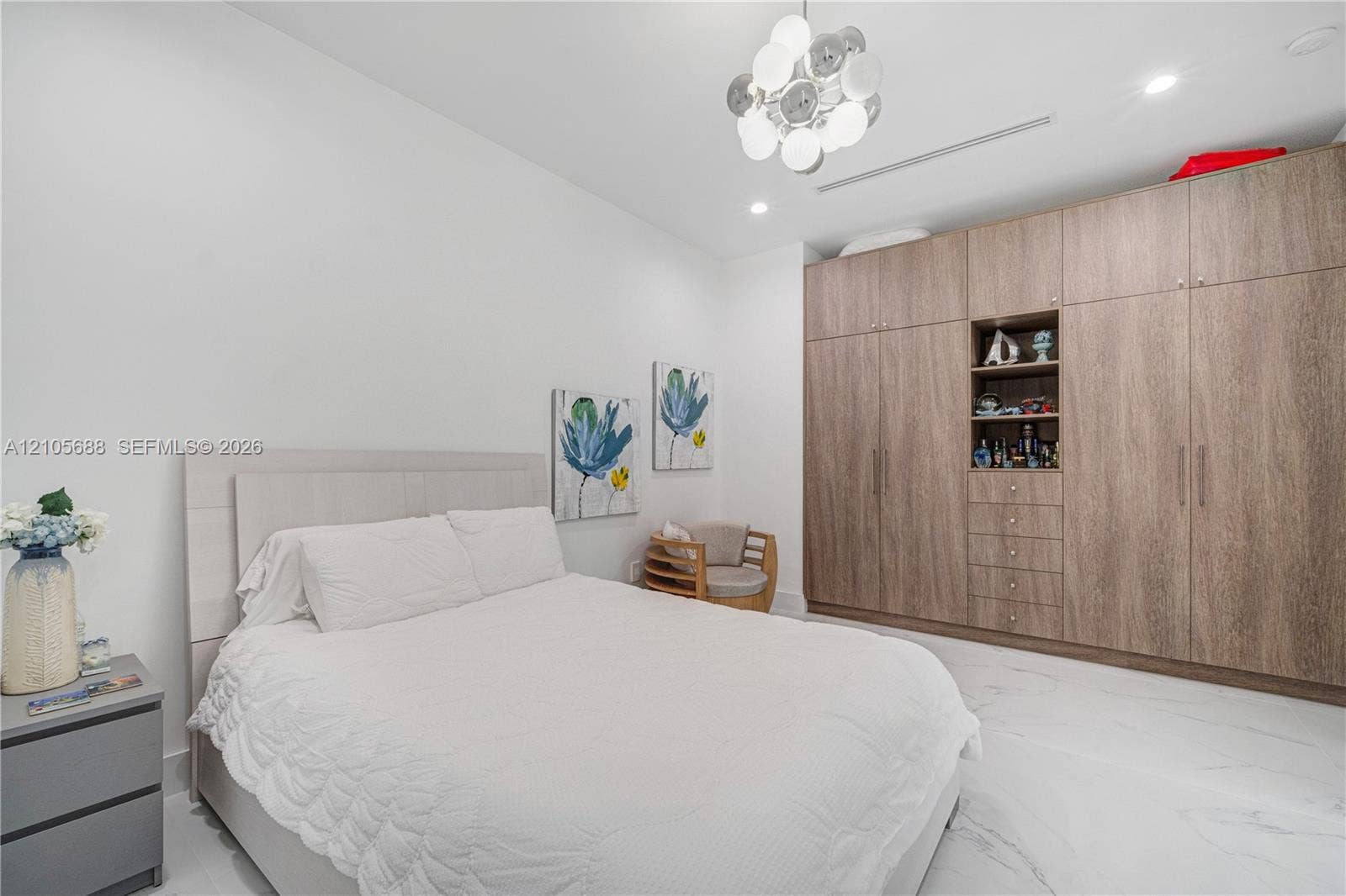 164 W Avenue C, Key Largo, FL 33037 Full-height built-in wood-finish cabinetry featuring integrated open shelving and drawers, polished white stone-finish flooring, and a modern multi-globe chandelier