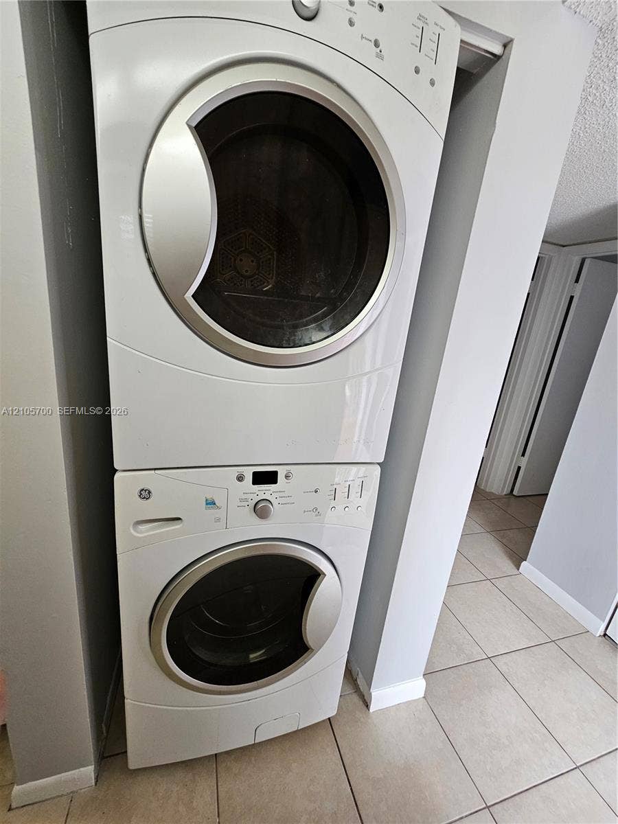 Stacked white front-load washer and dryer unit with metallic trim