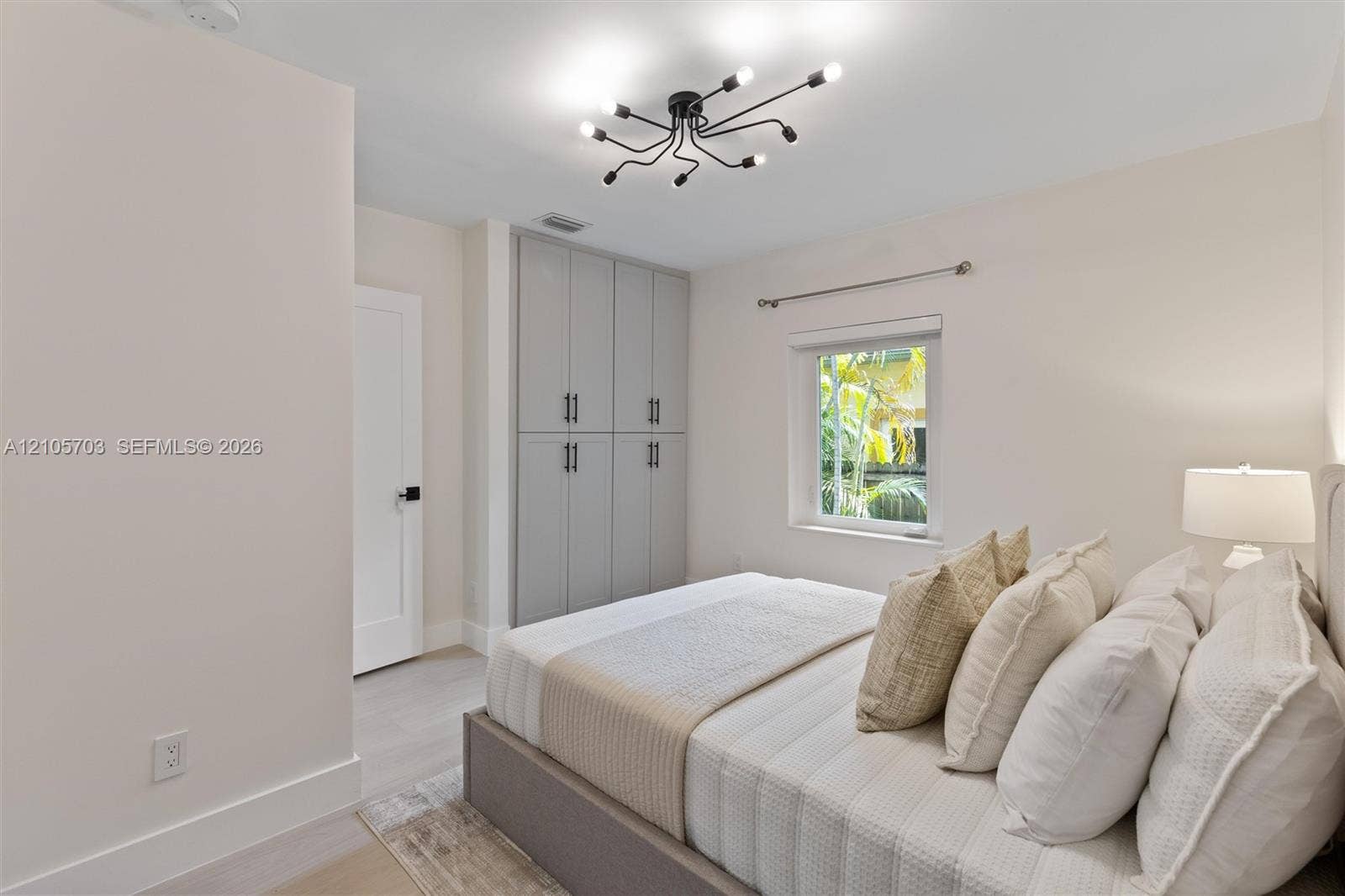 190 NW 102nd Street, Miami Shores, FL 33150 Multi-light spider chandelier, built-in floor-to-ceiling cabinetry with matte black hardware, and wood-finish flooring