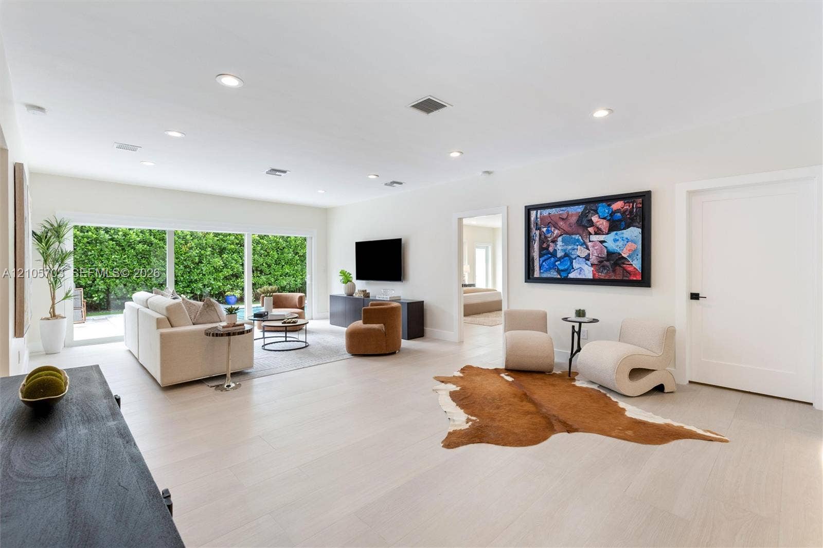 190 NW 102nd Street, Miami Shores, FL 33150 Open floor plan featuring light-toned wood-finish flooring, recessed lighting, and large sliding glass doors providing outdoor access