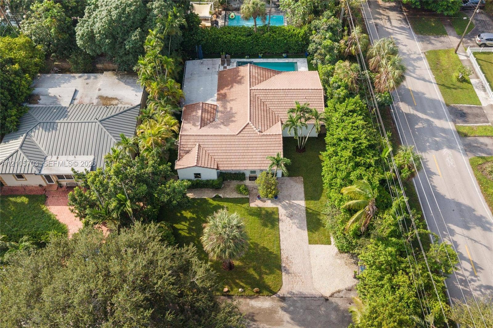 190 NW 102nd Street, Miami Shores, FL 33150 Aerial view featuring a tile roof, an in-ground swimming pool, a concrete patio, and a landscaped yard with mature trees